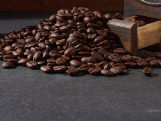 Antique vintage retro bronze coffee mill on black wooden board with roasted coffee beans