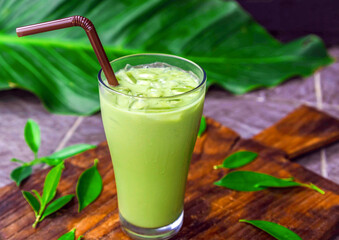 iced matcha latte, green tea with milk in a  glass with ice on wooden