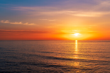 Obraz premium view at sunrise or sunset in sea with nice beach , surf , calm water and beautiful clouds on a background of a sea landscape