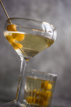 Close-up of a vodka cocktail and a tumbler filled with yellow glace cherries