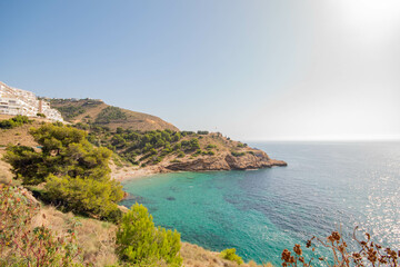 Panorámica de una de las preciosas calas con el agua turquesa de Benidorm bajo un soleado día de otoño con naturaleza al rededor.