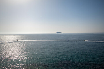 Panorámica del mar Mediterráneo desde uno de los punto más alto de Benidorm con la isla en el fondo bajo un día soleado.