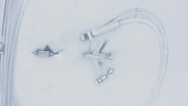 Fuel truck refueling private business jet during white winter snow conditions, aerial