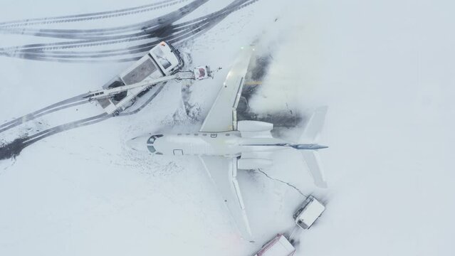Deicing business jet wing in snowy winter conditions, top down