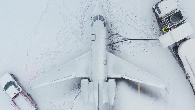 Top down view business jet being refueled by fuel truck, winter season