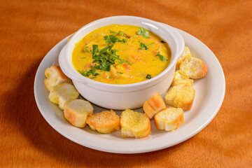 Shrimp broth with toasted bread on a wooden table. Traditional Brazilian appetizer.