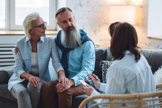 Senior Couple, Mature Man And Woman, Husband And Wife Sitting On The Sofa On The Therapy Session At Psychologist Cabinet, Discussing Stress, Family Problems