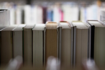 View of books on a shelf in a library with a blurred foreground and background.