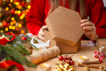 Close up of paper box present in hands of a girl. Female preparing gift for Christmas for friends...