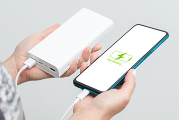 Smartphone in womans hands is charging from powerbank. Concept of fast charging, universal USB 3.1...