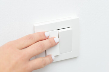 Turning on and off the light in the room with white walls. Close up picture of female hand on light...