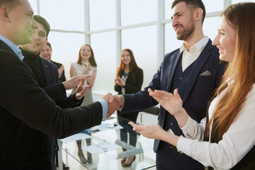 business partners shaking hands with the applause of the business team .
