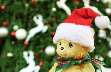Adorable Baby Lion Toy in Santa Hat with Blurry Christmas Tree in the Backdrop