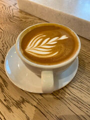 Cup of cappuccino with beautiful latte art on wooden table. Flat lay style. flat white.