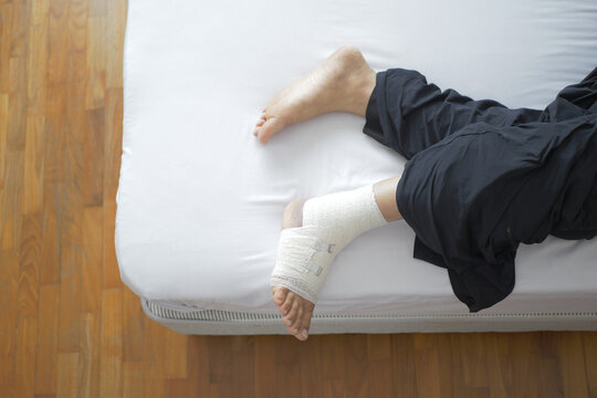 Woman with bandaged foot on bed top view 
