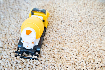 A kid  is playing with a yellow plastic concrete mixer truck toy in the cork pool.