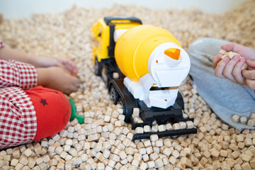 A kid  is playing with a yellow plastic concrete mixer truck toy in the cork pool.