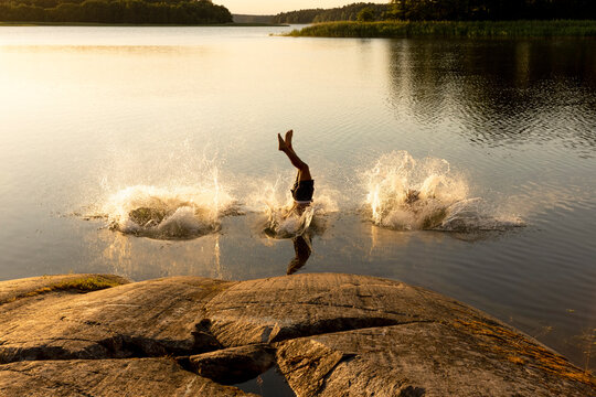 Man diving and splashing water in lake at sunset