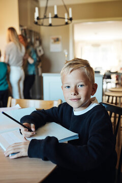 Portrait of smiling boy sitting with workbook on table at home