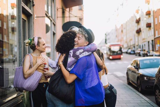 Happy young man with eyes closed hugging female friend in city
