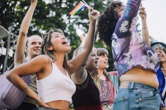 Happy friends with rainbow flags shouting during LGBTQIA rights parade