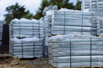 Pavers are packed in pallets near the construction site.