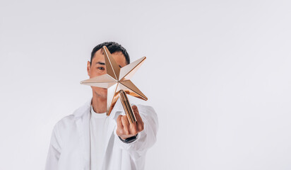 Porter of a young Asian man in white, middle finger with star raised up, abstract symbol of Christmas tree
