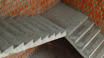 Concrete stairs in a new building near a brick wall. Start of construction.