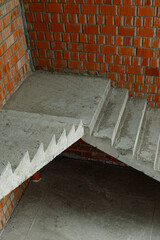 Obraz na płótnie Canvas Concrete stairs in a new building near a brick wall. Start of construction.