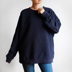 Woman wearing oversized navy sweatshirt and blue jeans isolated on white background