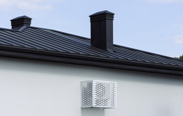 White metal protection of the air conditioner on the light wall of the house