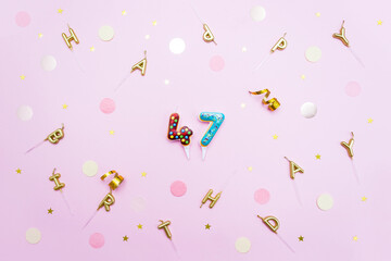 The number 47 in the shape of sweet donuts is surrounded by birthday party decor. Concept of celebrating forty-seven years. Selective focus
