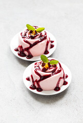 Vegan dessert. Plum cream pudding, Panna Cotta with sauce, in the shape of a rose, on a plate. Light grey background