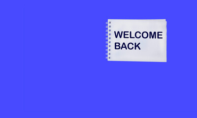 Notepad with WELCOME BACK text on laptops on beautiful blue background