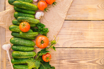Fresh vegetables on a wooden background. Empty space for the text. Cucumbers, tomatoes, garlic, dill. Top view.