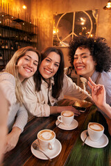 Vertical photo of Three female friends take a selfie while having fun a drink in the cafeteria....
