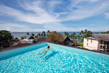 woman swimming in the infinity pool of luxury resort hotel with sea view, enjoy luxurious lifestyle