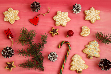 Christmas background: Christmas decor - branches, sleigh, caramel, toys, gingerbread, cones - on a pink background, top view