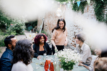 Smiling woman talking to friends during social gathering in back yard