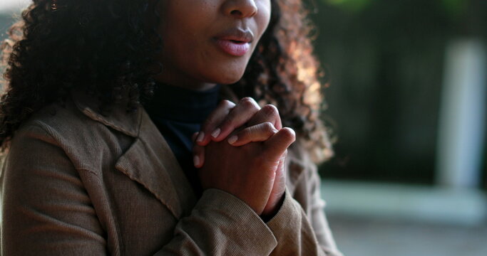 African woman praying to God outside seeking faith and HOPE outside in sunlight