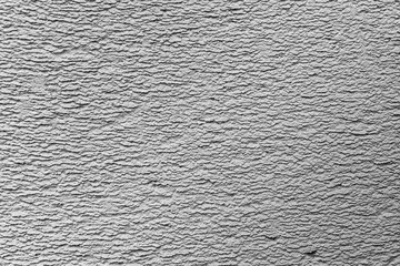 A fragment of a wall covered with gray plaster with relief