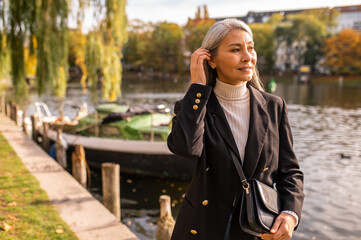 Smiling pretty woman in a black coat in the city street