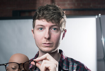 A young trendy stylish handsome male staring straight into the camera. A Young hipster student thinking and pondering about life and the future after graduation. No expression staring ahead.