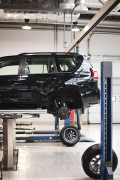Car lifted in automobile service for fixing, worker repairs detail
