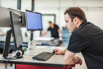 An experienced technician works on a printer computer in a printing shop. Production work. Check...