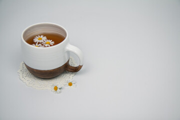 Chamomile tea in a white clay cup on a light background