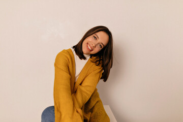 Adorable smiling happy girl with dark hair wearing white shirt and yellow jacket posing over isolated background 