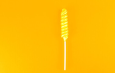Yellow and white spiral lollipop on a yellow background