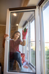 The girl washes the glass on the window