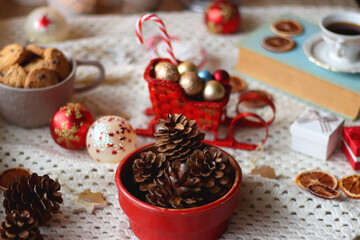Various colorful Christmas decorations, soft blanket, cup of tea, sweet snacks and lit candles on the table. Cozy Christmas atmosphere at home. Selective focus.